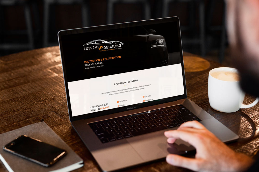 ordinateur montrant la première page d'un site de detailing posé sur une table de café